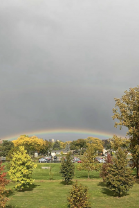 Photo of a rainbow above a green space. 