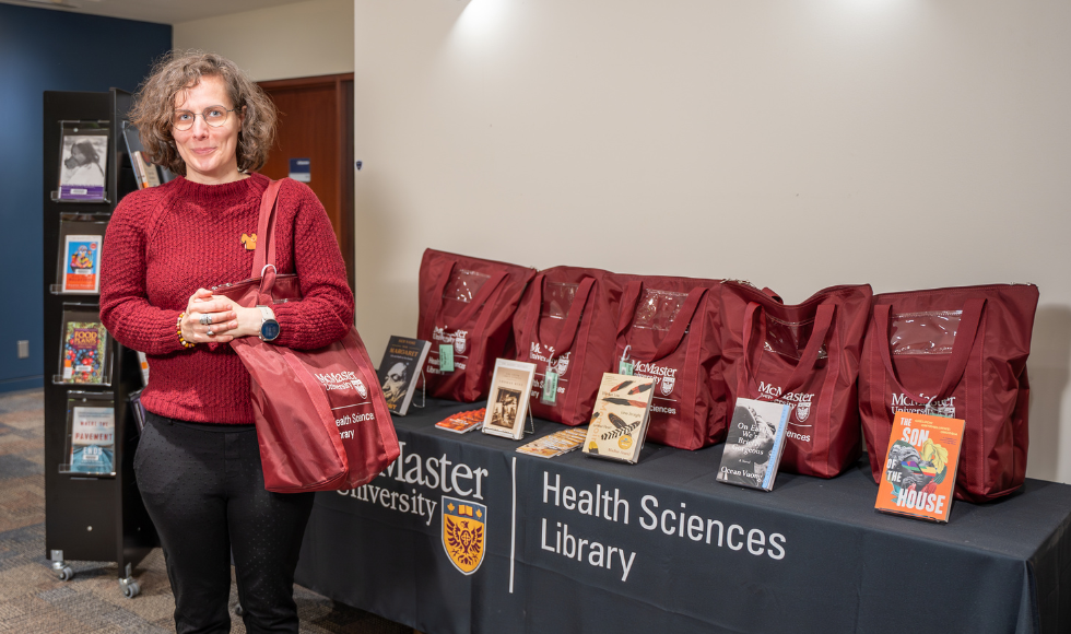 Health Sciences librarian Laura Banfield standing next to Host Your Own Book Club Kits focused on equity, diversity and inclusion.